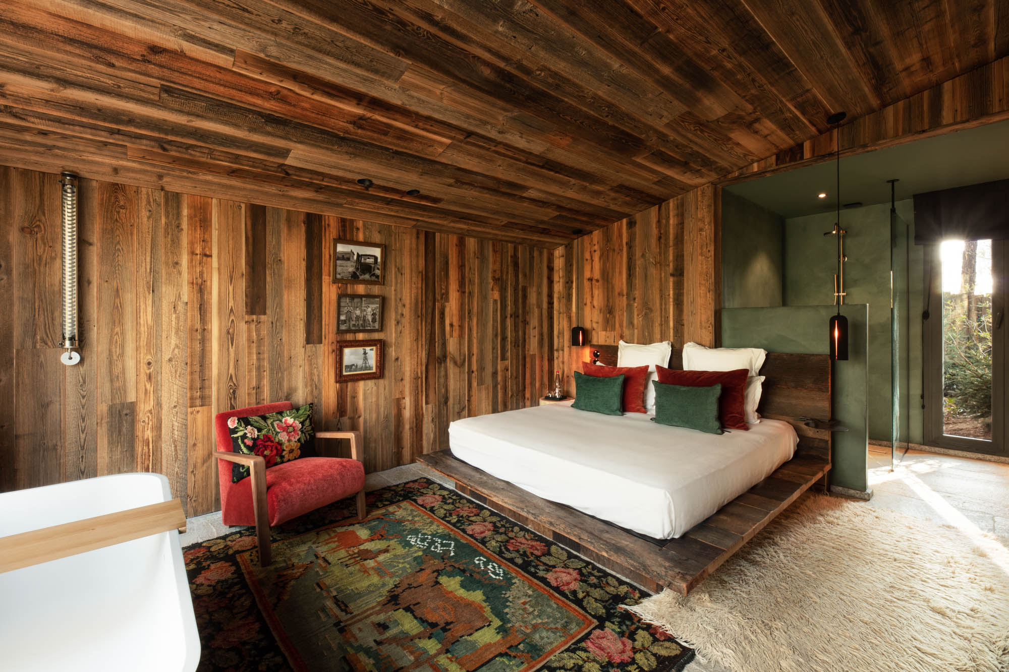 chambre aux murs en lambris bois et salle de bain ouverte avec une douche italienne