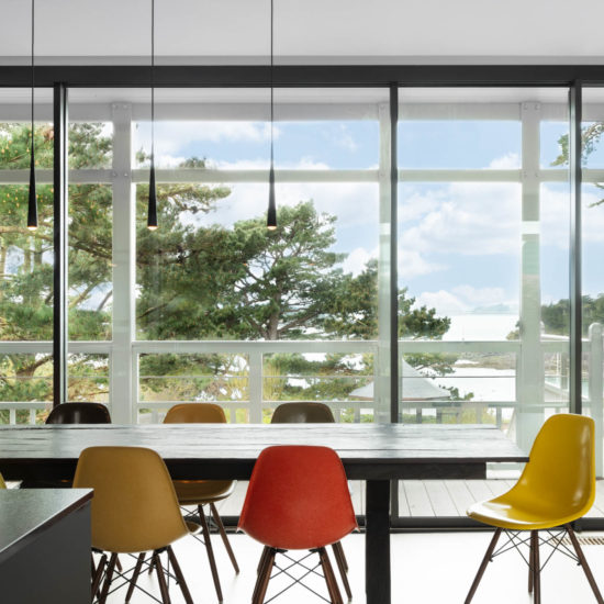 salle à manger aux chaises colorées et baies vitrées donnant sur la mer