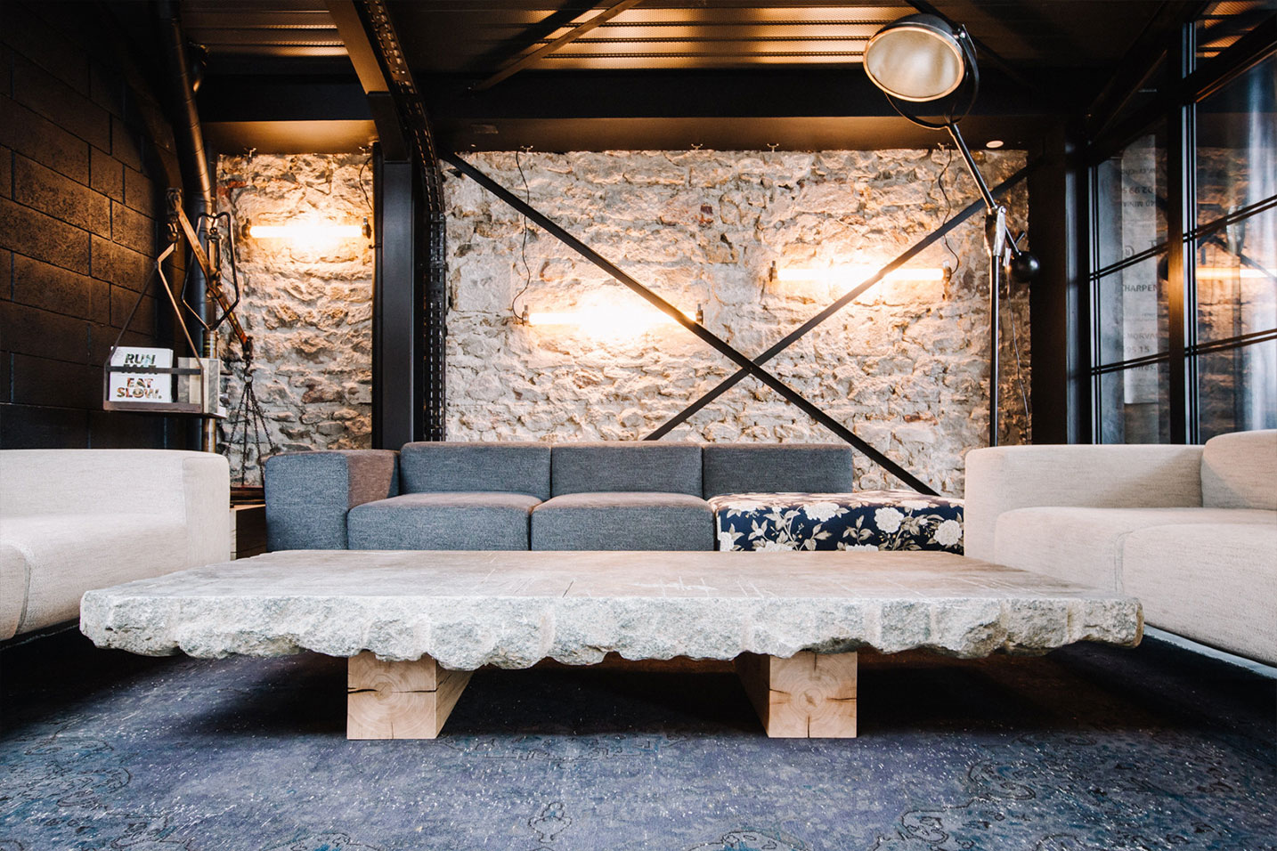 salon d'un restaurant avec une table en pierre et des fauteuils beiges et gris