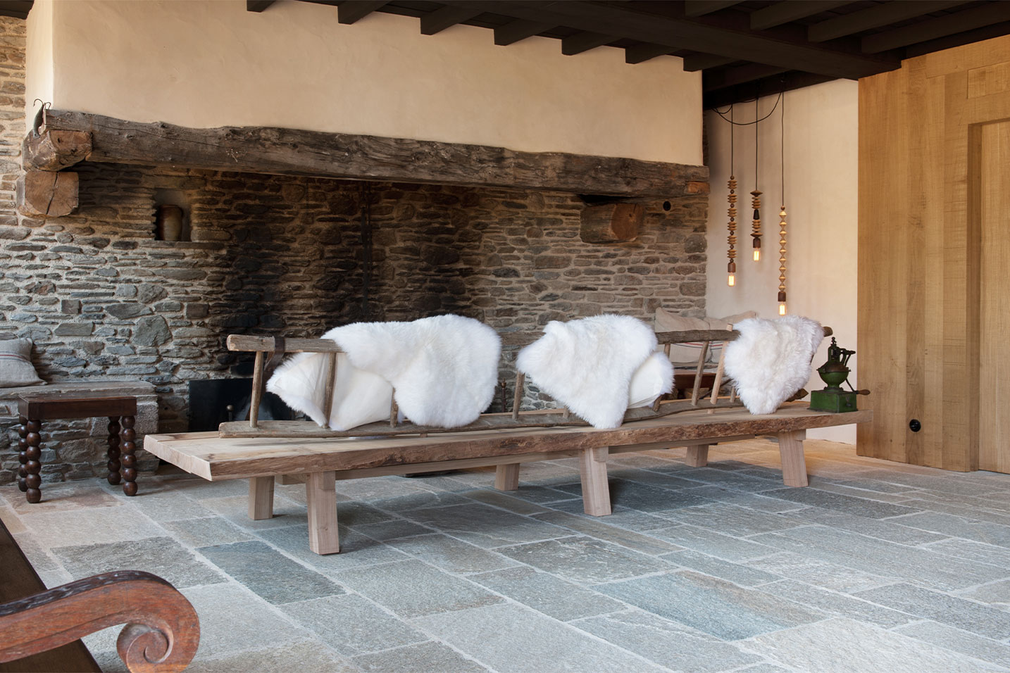 maison aux murs en pierre et au banc en bois avec une décoration tapis polaire