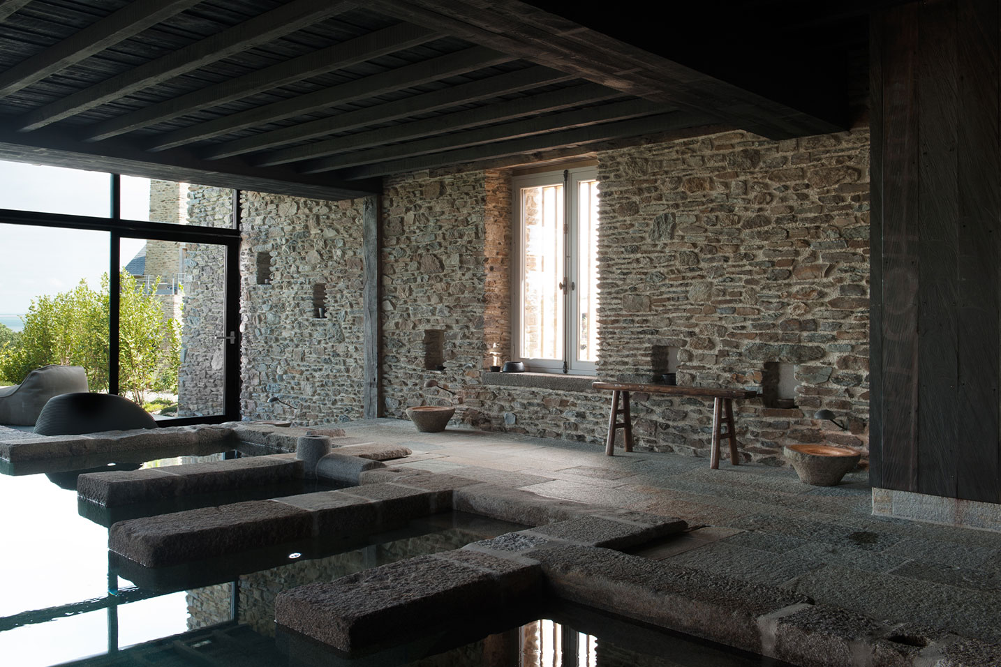 villa en pierre avec une piscine intérieure et extérieure