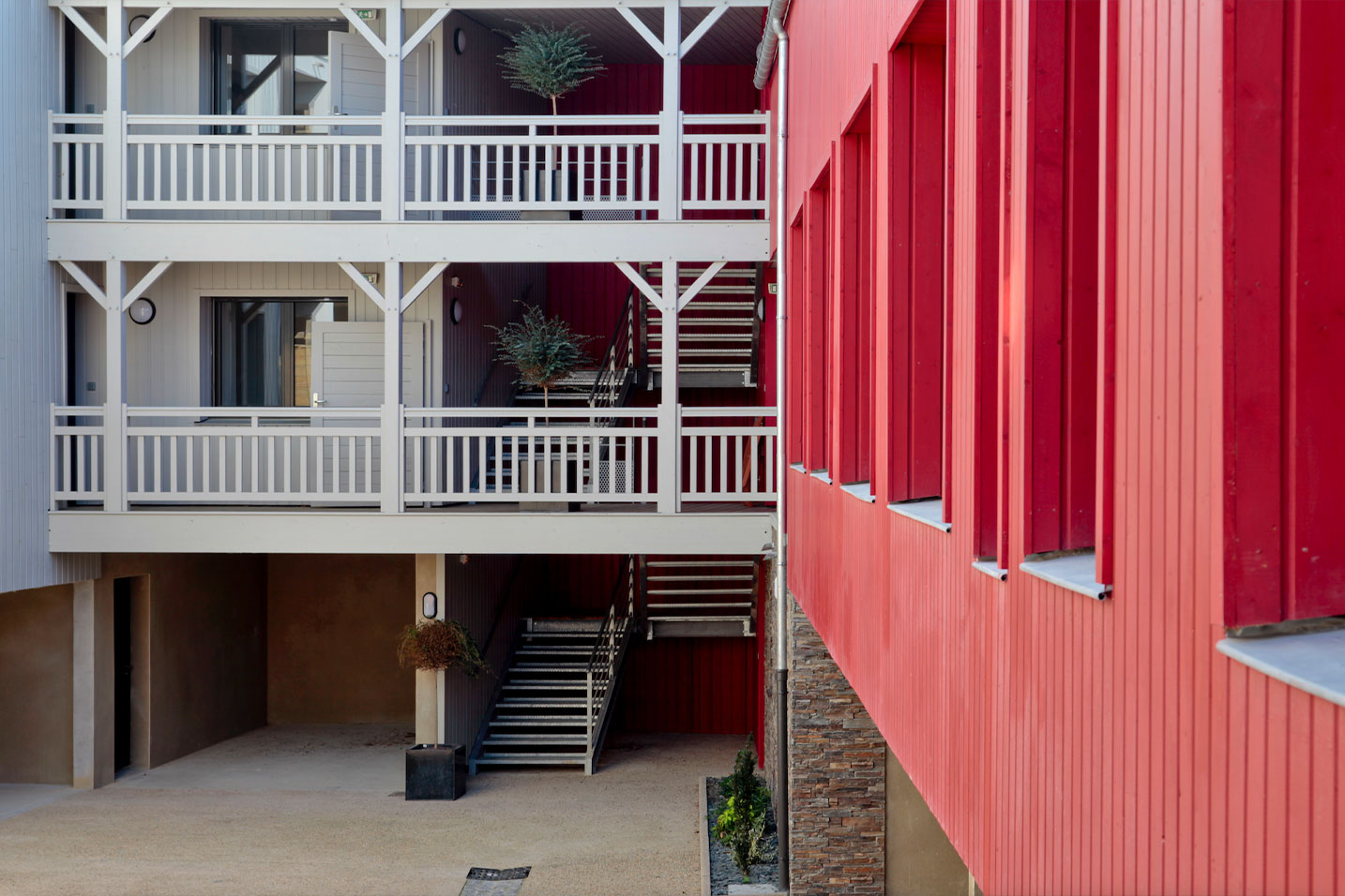 cour intérieur d'un collectif avec une façade en ventelles rouges