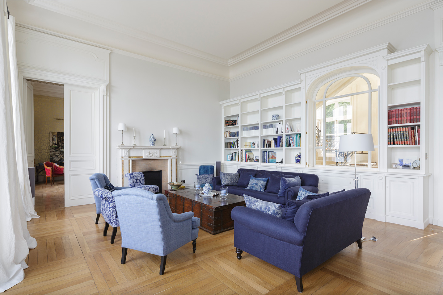 salon avec un parquet en bois et plusieurs fauteuils bleus