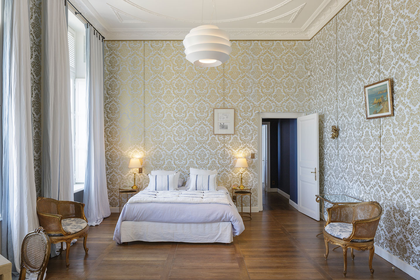 chambre avec une tapisserie dorée et une hauteur sous plafond